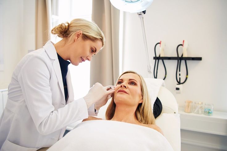 Doctor and assistant doing botox injections on a mature woman